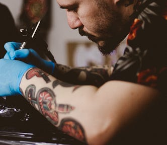 Tattoo artist creating a tattoo on a person’s neck