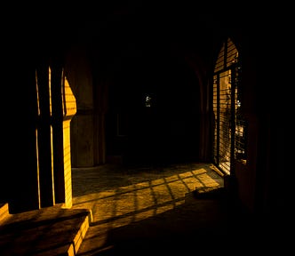 A gloomy cell with bars and a yellowish light shining through