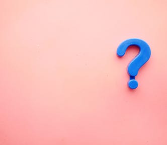 A blue question mark on a faded pink background