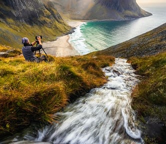 a river flows down a mountain to the sea where a photographer sits