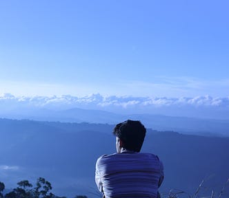 a person sitting on top of a mountain staring out