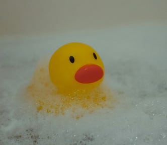 A rubber duck sat in a bathtub covered with bubbles.