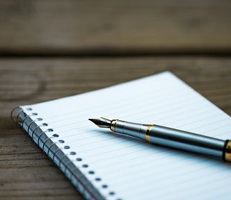 A fancy pen lying on a blank notepad