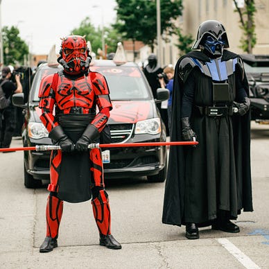 Two Star Wars cosplayers, one dressed as Darth Maul, the other dressed as Darth Vader.