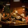 A small family — man, woman, and boy, clink glasses over a restaurant table. They all look relaxed and happy.