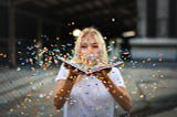 A woman blows confetti from a book
