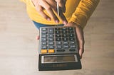 Close up of a woman’s hands holding a calculator and pen