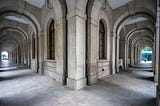 A hallway corridor that diverges into two separate paths, representing the gap between how institutions say they operate and how they actually do