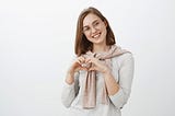 Mulher sorrindo e formando um coração com as mãos simbolizando uma boa experiência de compra