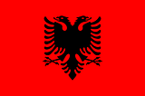 The flag of Albania, a two headed black eagle on a red background.