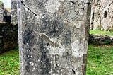 A gravestone with a Celtic cross, grey and lichen covered stone against the green mown grass. Bridgestone Priory. Cork. Ireland.