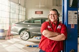 Portrait of Belle Tire employee in red uniform, posing in mechanic’s shop, by Chicago-based brand narrative photographer Nathanael Filbert.