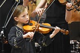 talented young woman playing violin in a concert hall