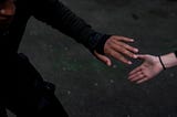 A color photograph by Brendan Davis of the hands of two people reaching for one another during an exercise routine.