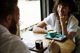 Man (left) and woman (right) in a conversation in a cafe