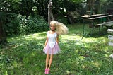 A barbie doll hanging on a tree by its neck.