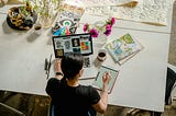Photo of Woman Writing on Tablet Computer While Using Laptop