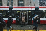People walking in the snow outside of a streetcar in downtown Toronto