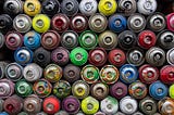 A pile of spray paint cans of many different colors