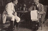 An image of two men reading a script in 1920