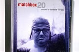 Album Cover for MatchBox 20 featuring a man in a fitting leather cap with glasses with his eyes closed. The cover is an indigo color.