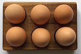 half a dozen brown eggs in a carton