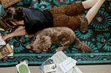 Linea laying on the floor reading surrounded by books and her dog