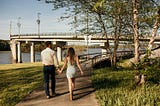 holding-hands-walking-under-bridge-at-Two-Rivers-Park