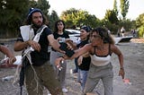 Alice Kisiya (right, front) confronts a settler holding a phone (left, front).