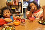 Two little girls eating Campbell's soup.
