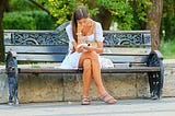 A woman quietly reading a book on a park bench