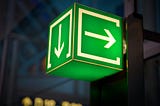 A green sign in the shape of a box with arrows on each side lighting up