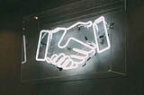Image of neon sign of hands shaking