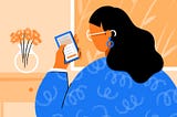 This is an illustration. A woman looking at a smartphone that she is holding in her hand. She wears glasses and is covered in blue cloth. There is a flower vase in front of her. And the background is light orange.