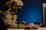 Soldier sitting at computer conducting drone warfare
