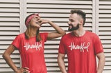 Photo of man and woman in red shirts that say thankful on them