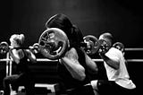 Black and white picture of two women and one man doing split squats while weightlifting. Alex2Cents.com.