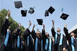 A group of university students are throwing their hats up in the air at their graduation