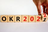 A series of wooden blocks in a row, which spell out “OKR 2022”, changing from 2021.