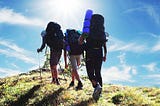 team backpacking up a ridgeline toward the summit.