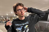 man with glasses wearing a whales shirt in parking lot