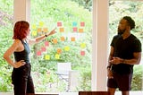 Colleagues discuss work while handling physical sticky Kanban notes