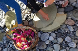 Women’s hands gathering flowers and leaves for making offerings during a seaside ceremony