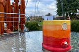 Colorful mug with a broken handle sitting on a table outside