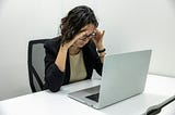 a woman sitting in front of a laptop computer suffering from toxic productivity