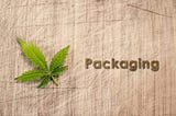 cannabis leaf and the word packaging on a wood background