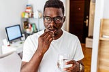 Man holding glass of water and taking a collagen supplement