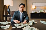 CEO of a company wearing a business suit, sitting in an executive suite in a fancy luxury hotel, looking serious, counting cash.
