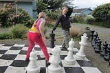 two children playing chess on a life-size outdoor chess-board