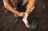 a man wrapping his foot before a workout due to pain